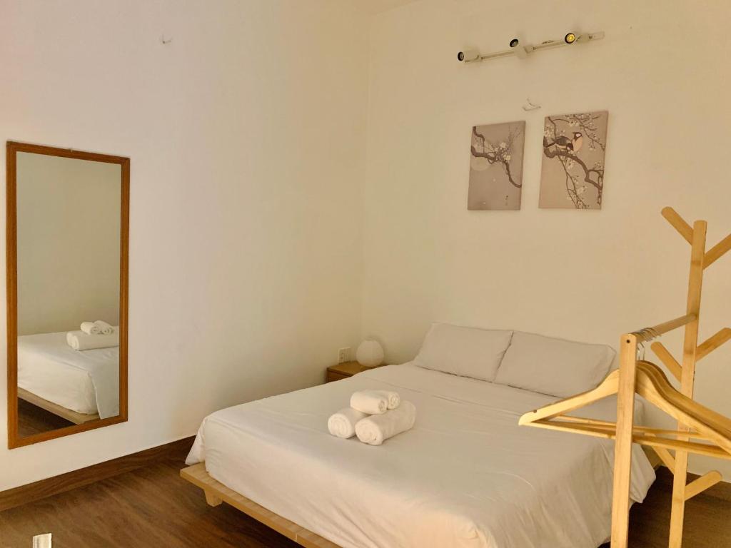 1 dormitorio con cama blanca y espejo en The Hideaway Alley Bui Vien, en Ho Chi Minh