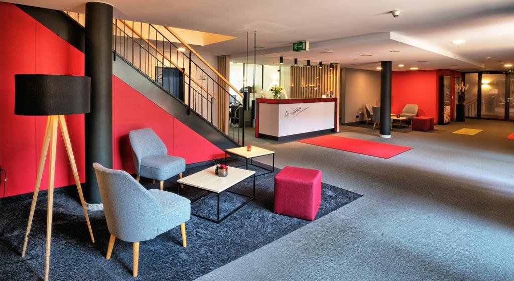 a lobby with a red wall and chairs and a screen at Hotel & Apart4you in Dorfen