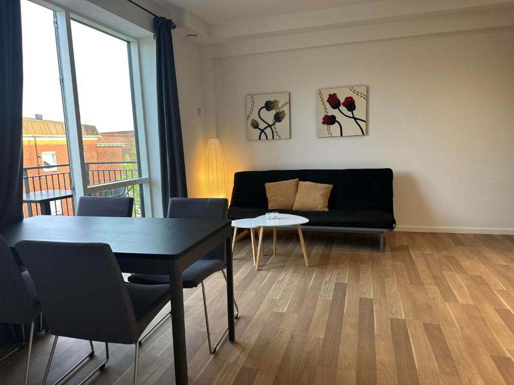 a living room with a black couch and a table at City Apartment Dæmningen Vejle in Vejle