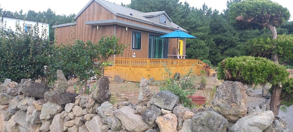 a house behind a rock wall in front of a house at Hamdeok Pool Villa Ferrari in Jeju