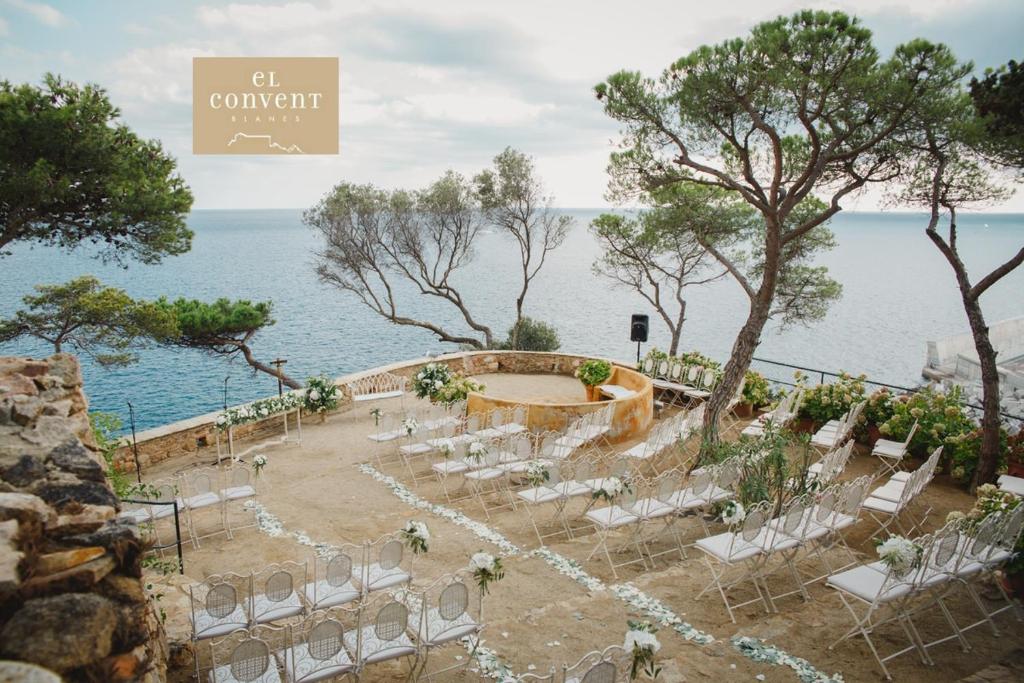 an outdoor wedding with white chairs and the ocean at Apartament 'Es Botànic' in Blanes