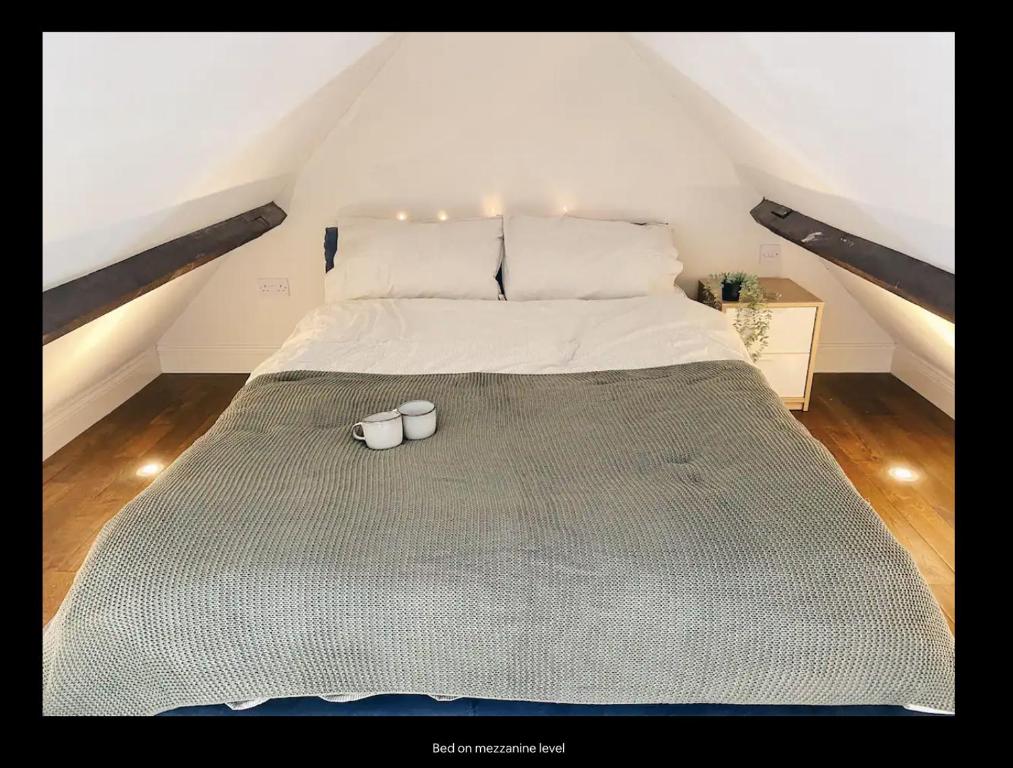 a bed with two white cups on top of it at Mezzanine studio apartment (U9) in London