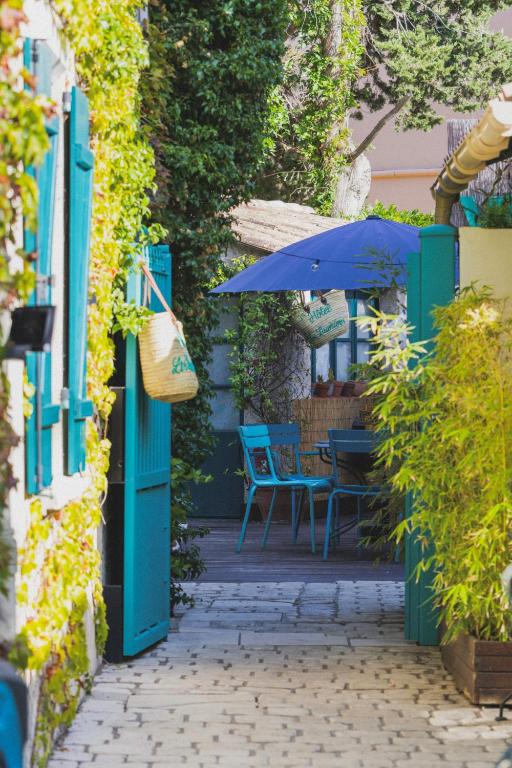 une terrasse avec une porte bleue et une table avec un parasol dans l'établissement Les Lauriers, à Saint-Tropez