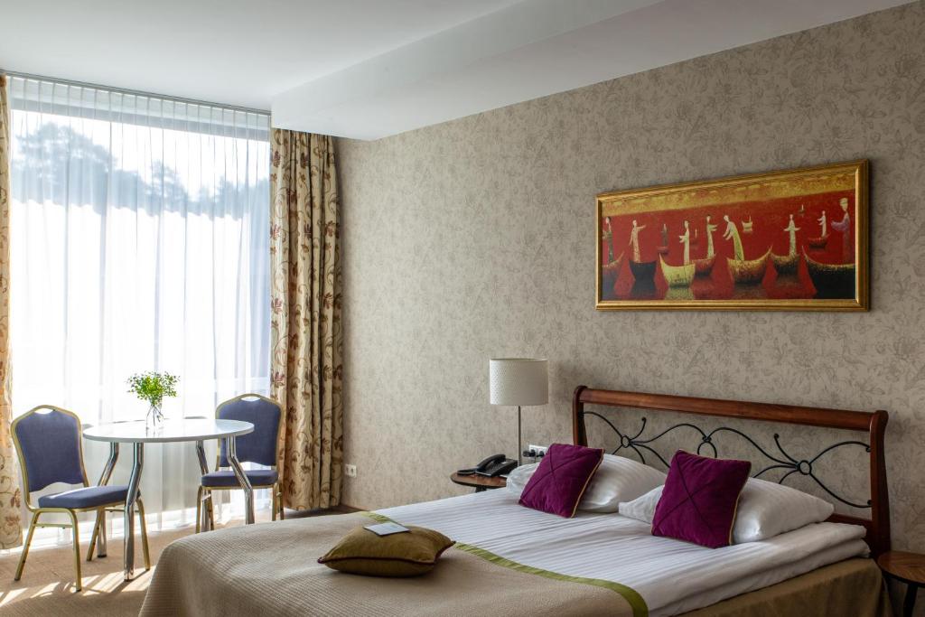 um quarto com uma cama e uma mesa com cadeiras em MEDEA Apartments by UPA em Druskininkai