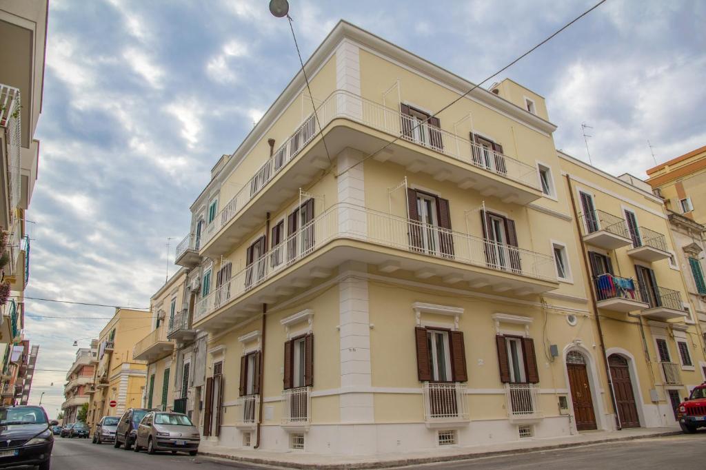 un grande edificio giallo con finestre su strada di DomusApuliae Apartments a Monopoli