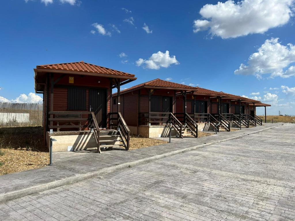 una fila de cabañas de madera al lado de una carretera en Motel 112, en Algora