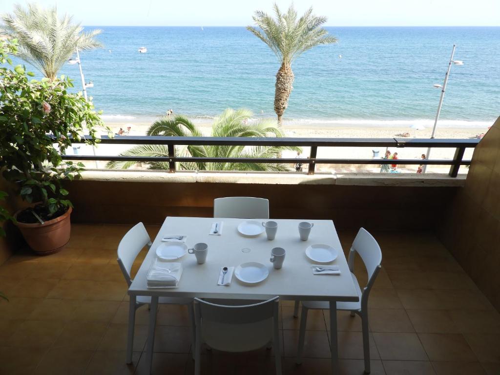 a white table with chairs and a view of the beach at Aguadulce Primera Línea - A/C in Aguadulce