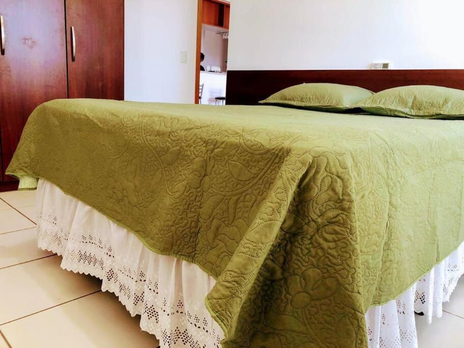 a bed with a green and white comforter on it at Lago Norte - CA 05 in Brasilia