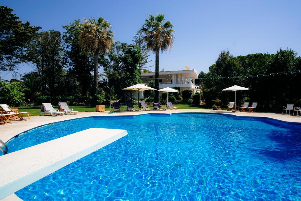 a large blue swimming pool with chairs and umbrellas at A Pausa in Alvor