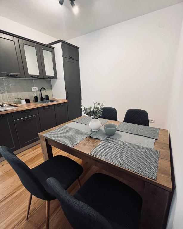 a dining room table with chairs and a kitchen at Gray apartman in Vrnjačka Banja