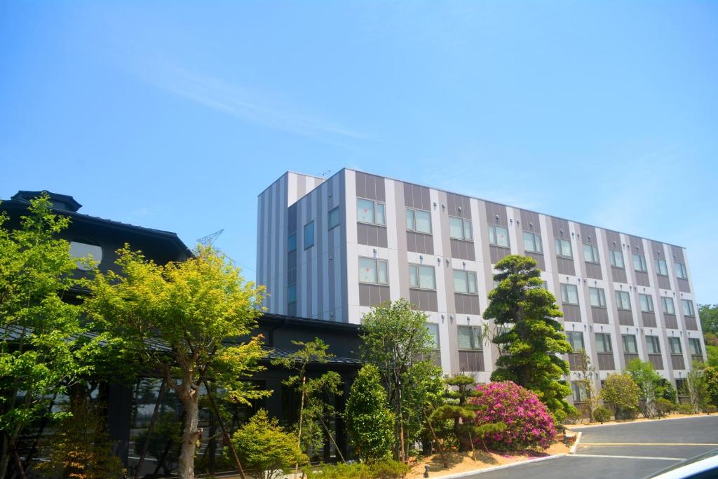 um alto edifício branco com árvores em frente a uma rua em Hotel Futabatei em Hirono