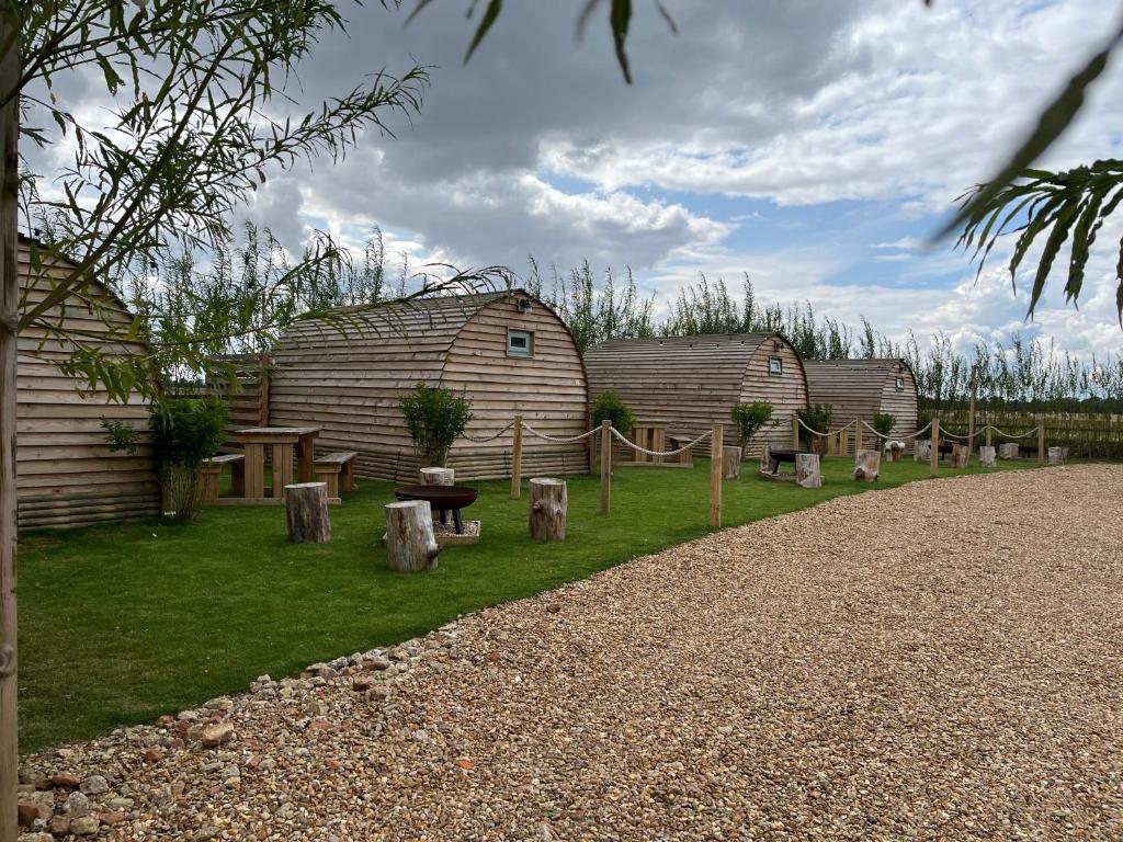 podwórze z dwoma stodołami, ławką i drzewami w obiekcie Wind In The Willows Luxury Glamping w mieście Peterborough