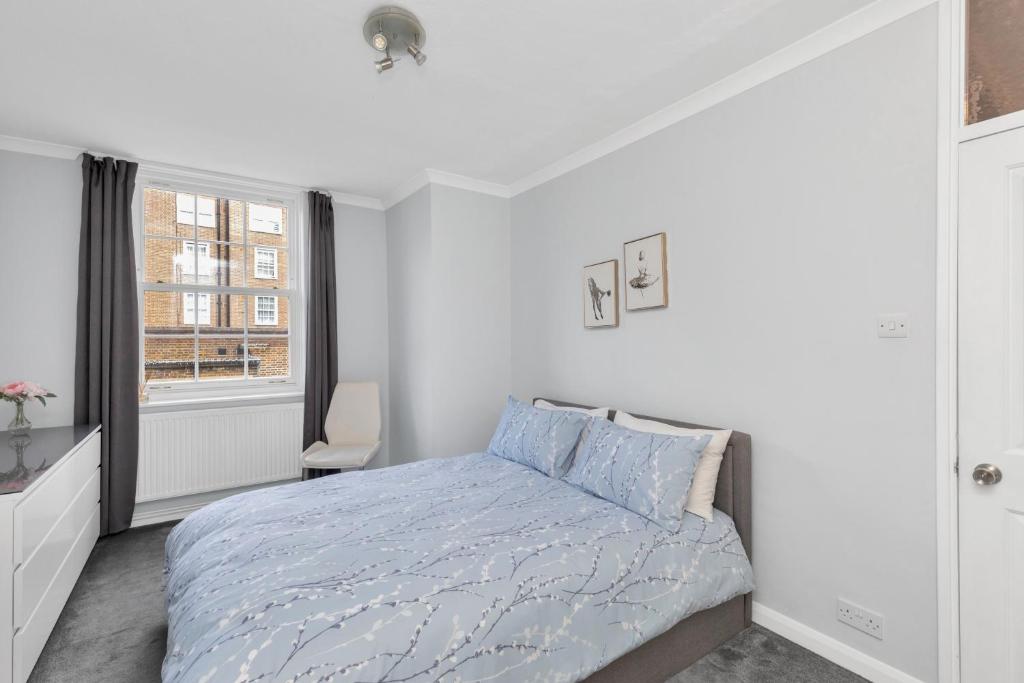 a white bedroom with a bed and a window at Entire flat in heart of Chelsea hosted by Zahra in London