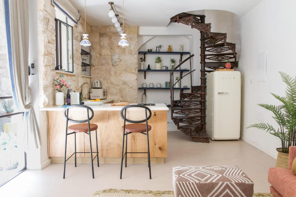 a kitchen with two bar stools and a refrigerator at David Zehavi Apt #2 in Tel Aviv