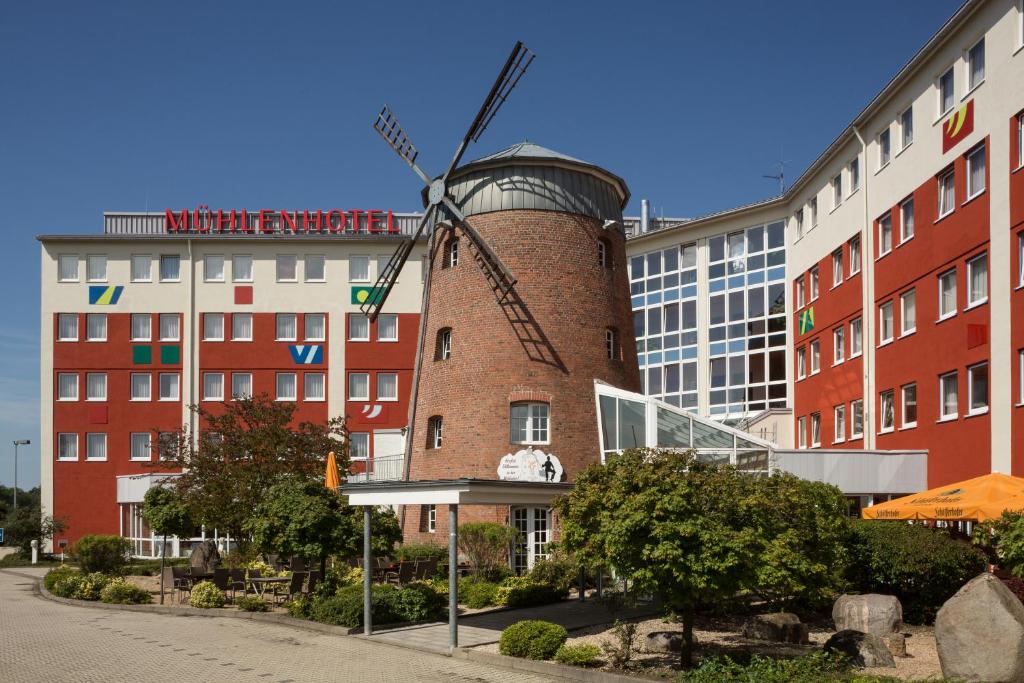 um edifício com um moinho de vento em frente a um edifício em Mühlenhotel Halle-Leipzig em Landsberg