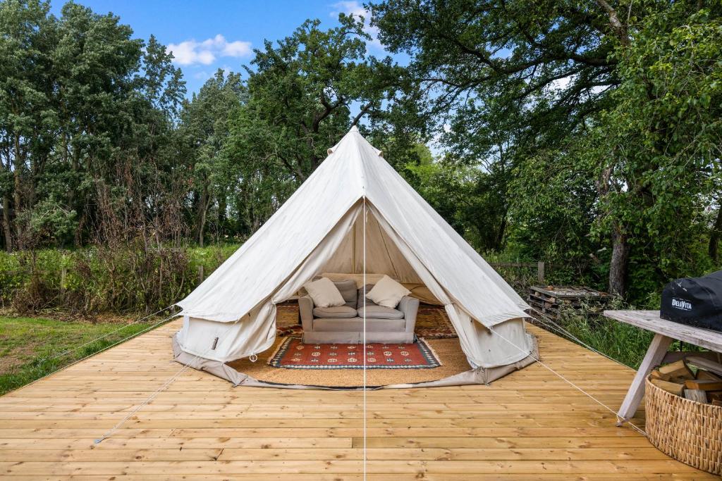 une tente avec un canapé sur une terrasse en bois dans l'établissement The Bell Tent - overlooking the moat with decking, à Evesham