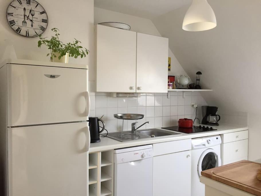 a kitchen with a white refrigerator and a clock on the wall at Plage de rêve et tennis devant la maison in Pornichet