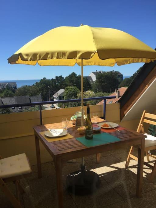 a table with a yellow umbrella on a balcony at Plage de rêve et tennis devant la maison in Pornichet
