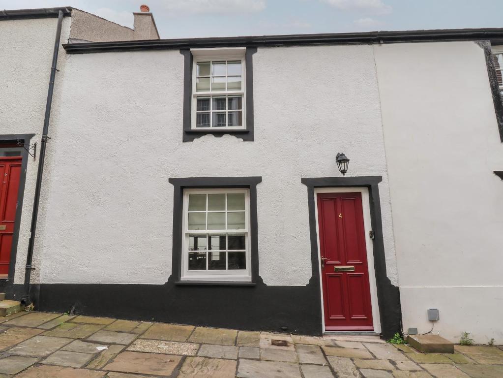 a white house with red doors and windows at Neptune Cottage in Conwy