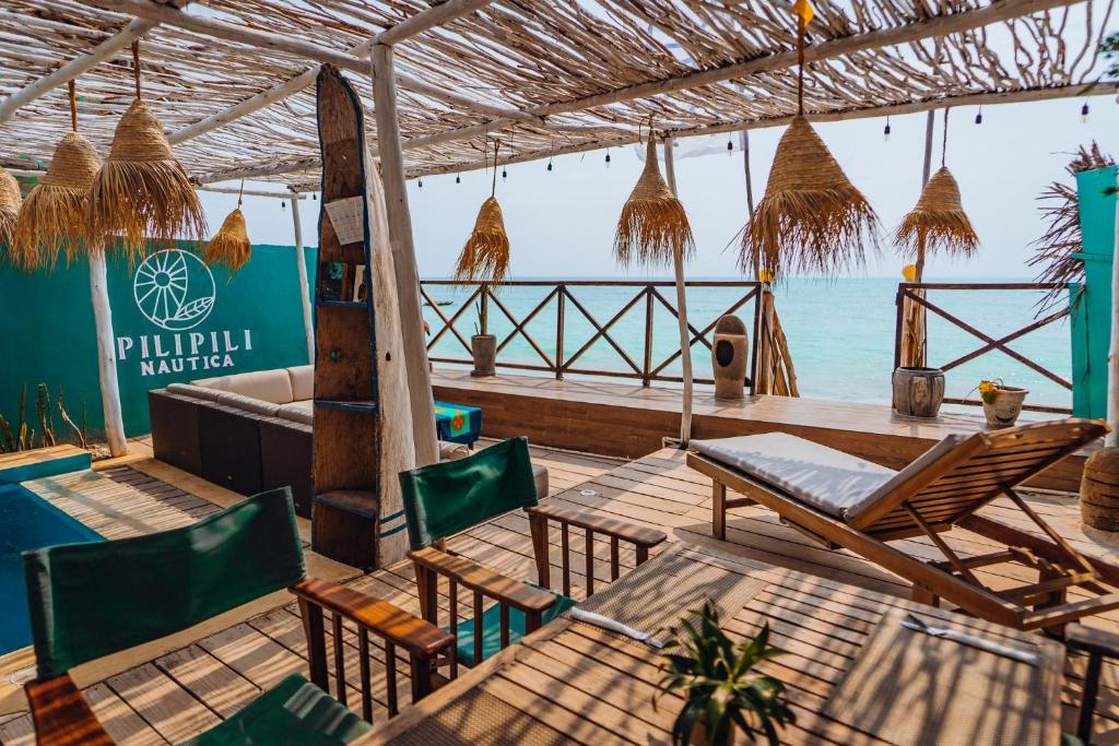 a patio with tables and chairs and the ocean at Pili Pili Boho in Jambiani