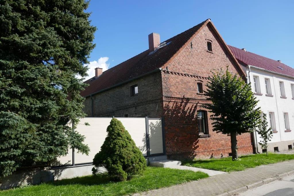 a brick house with a white garage in front of it at Ferienwohnung Sieben Eulen in Garrey (Hoher Fläming) 