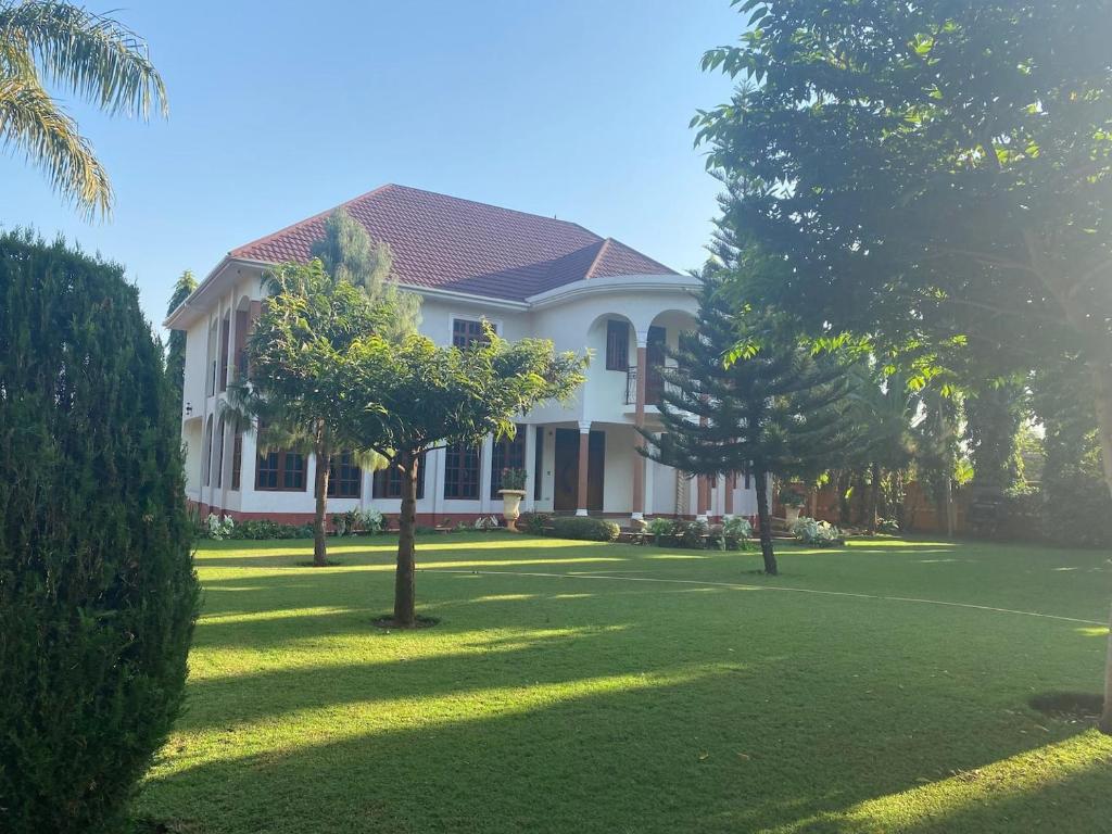 Une grande maison blanche avec des arbres dans la cour dans l'établissement Kilimanjaro Pazuri Villas, à Moshi