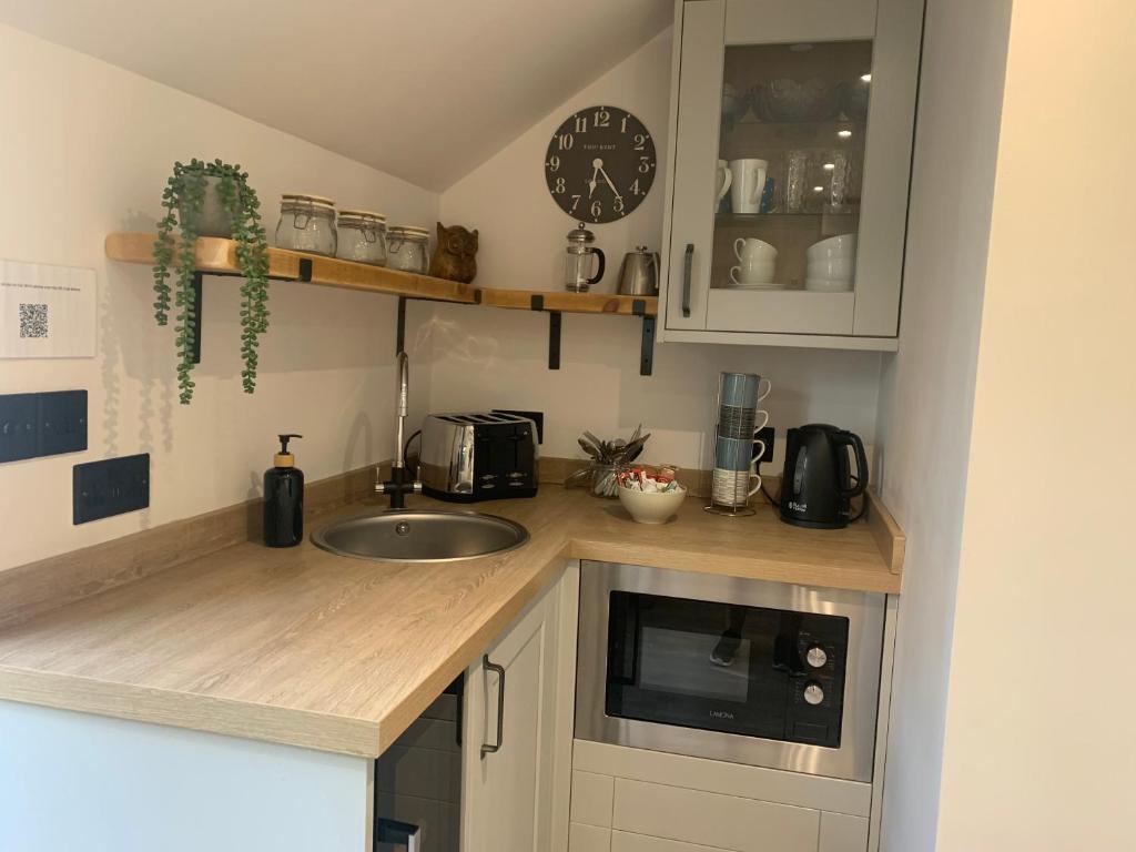 a kitchen with a sink and a clock on the wall at Robin's Nest - a self contained detached annex with sky sports & movies in Newborough