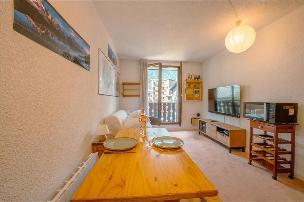 uma sala de estar com uma mesa de madeira e uma televisão em Chamonix Sud - Bâtiment Iris 374 - Happy Rentals em Chamonix-Mont-Blanc