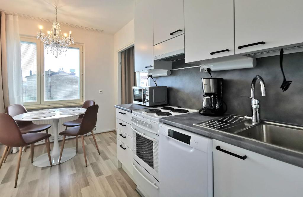 una cucina con elettrodomestici bianchi e un tavolo con sedie di Rovaniemi Cityhome Pekankatu a Rovaniemi