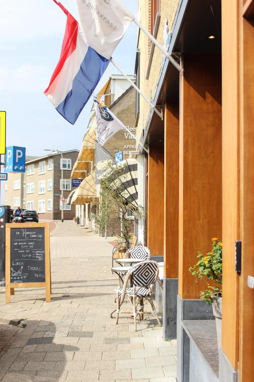 een straat met een tafel en stoelen en een vlag bij Hotel Steeds aan Zee in Katwijk
