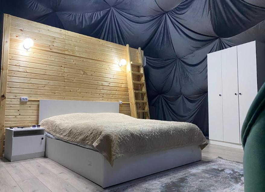 1 dormitorio con 1 cama y pared de madera en Shatyly Lake ViewGlamping en Bokonbayevo