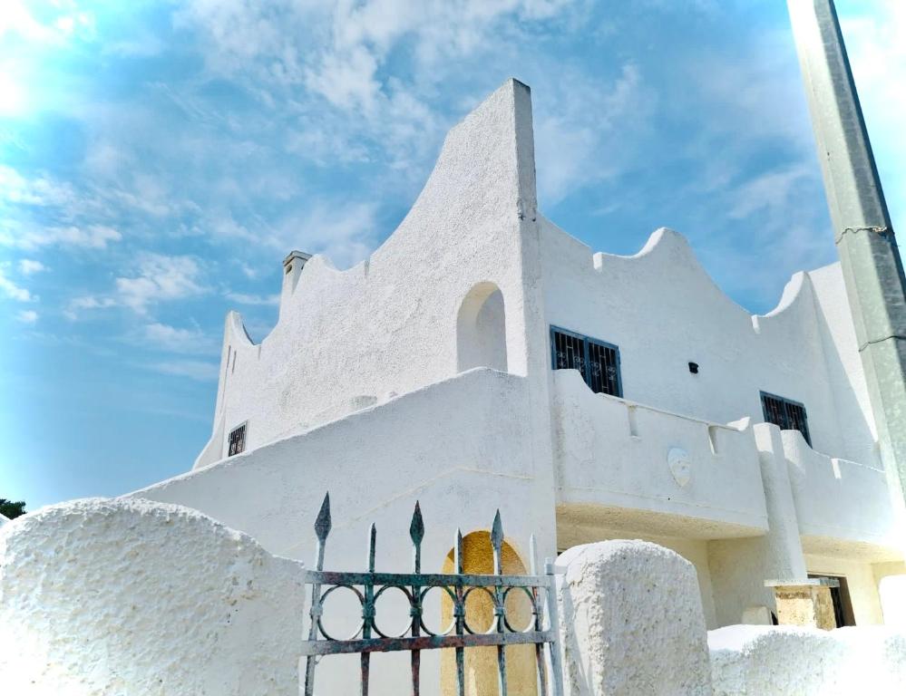 Ein weißes Gebäude mit einem Zaun davor. in der Unterkunft Dolce Casa in Casalabate