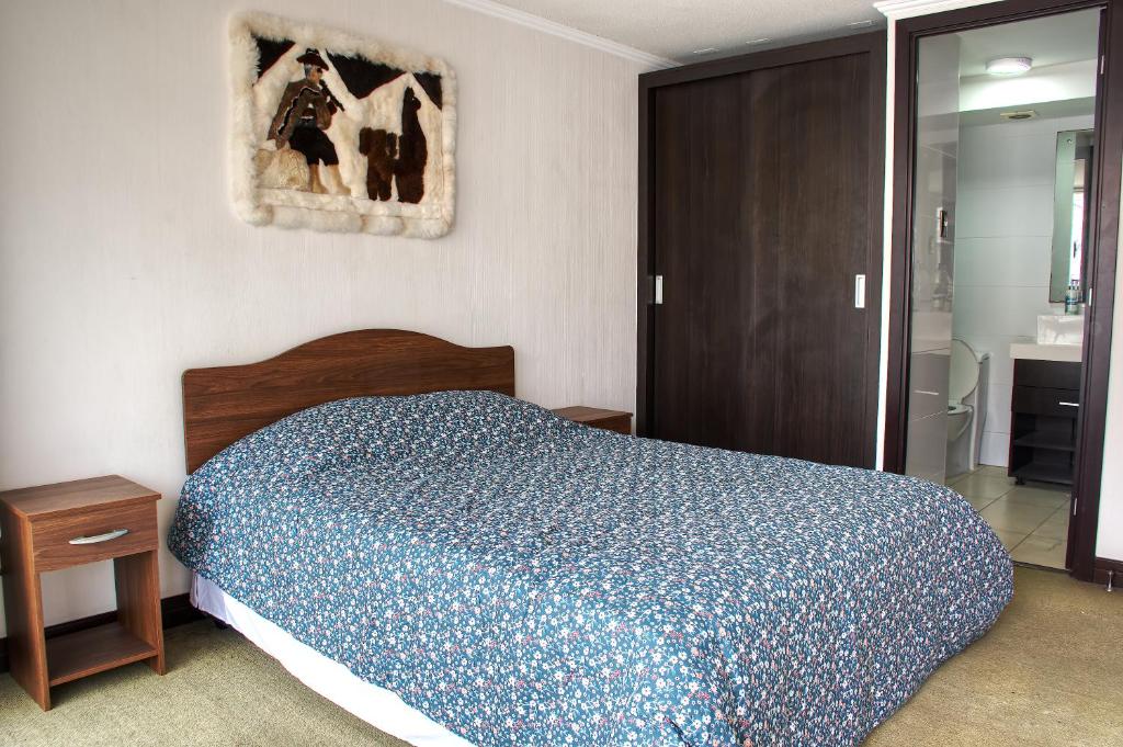 a bedroom with a bed with a blue comforter at Depto. Full equipado in Iquique