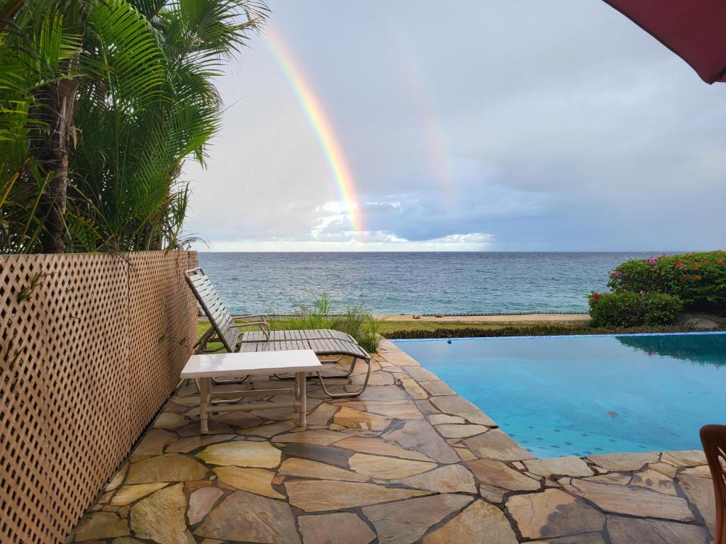 un arco iris sobre el océano con un banco y una piscina en Birdie's Nest, en Black Rock