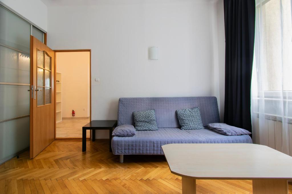 a living room with a blue couch and a table at Wondrous Apartment Warszawska street in Krakow