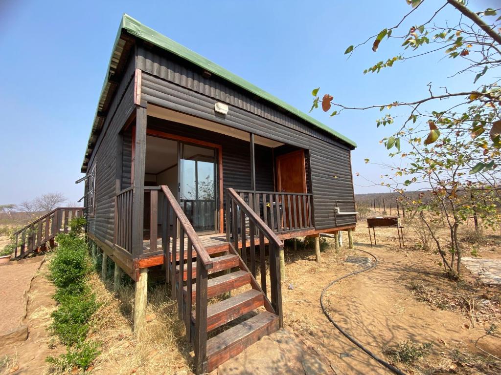 une petite maison avec une terrasse couverte et un escalier dans l'établissement Porcupine Cabin, à Palatswe