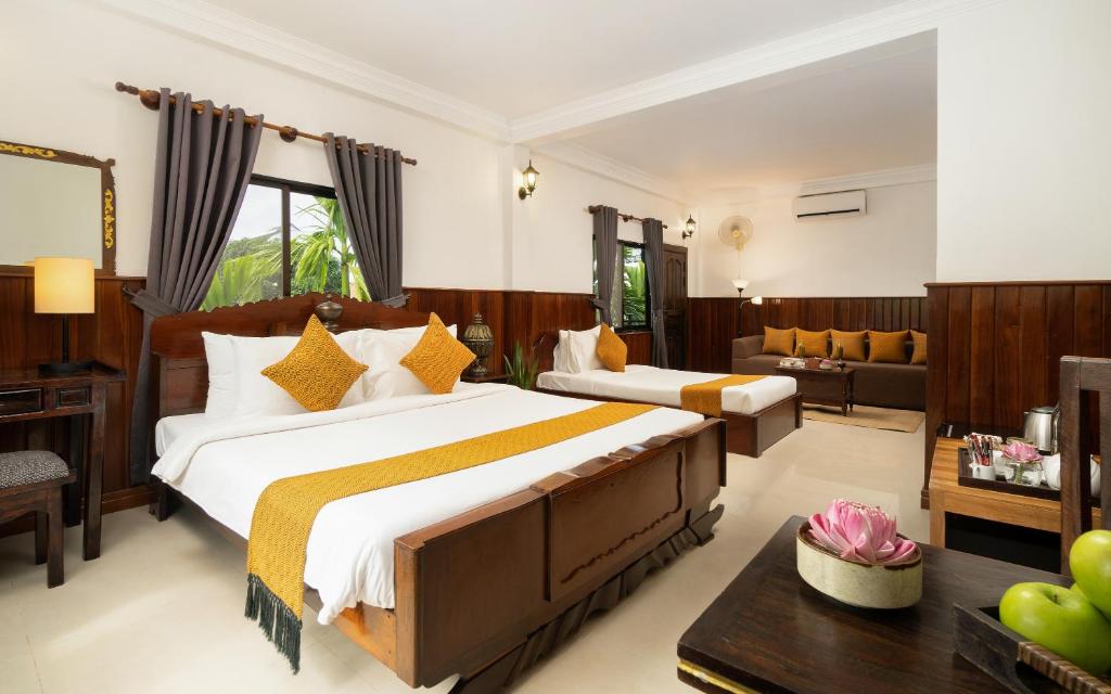 a bedroom with two beds and a living room at The Urban in Siem Reap