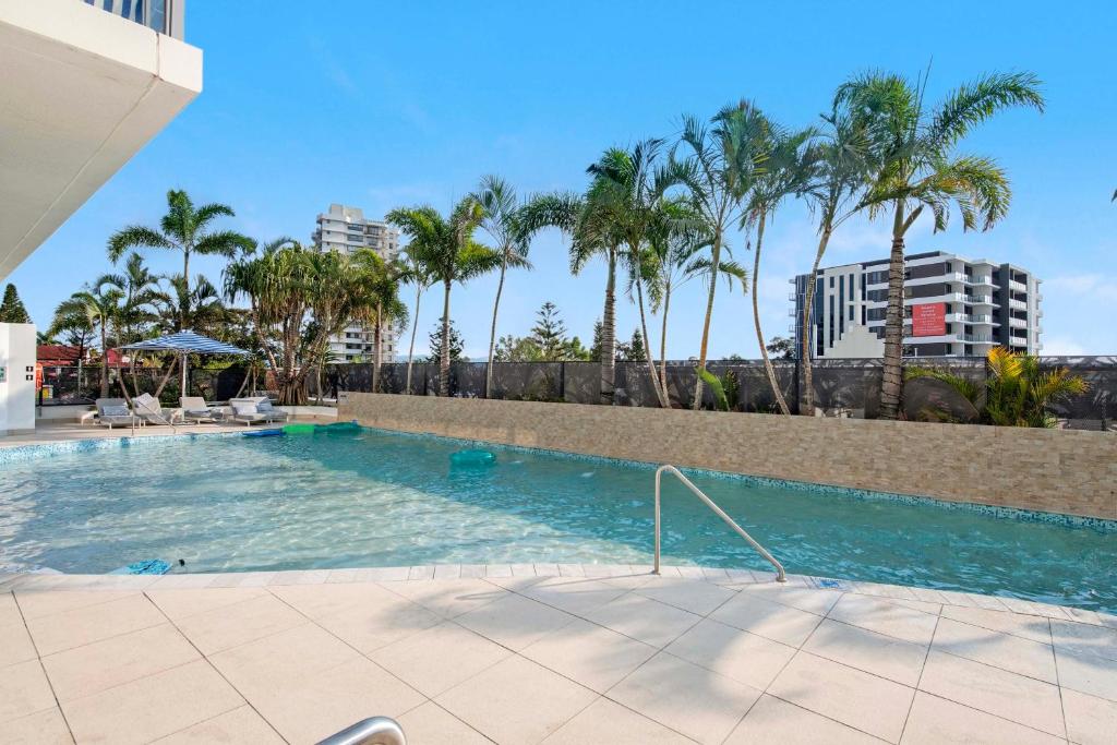 a swimming pool with palm trees in a city at Romantic Getaway in Surfers Paradise - Elston Apartment with Ocean View - Wow Stay in Gold Coast
