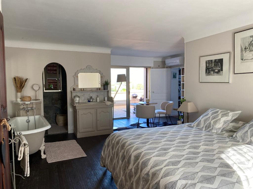 1 dormitorio con cama, bañera y lavamanos en Les Trois soleils, en Roquebrune-sur-Argens