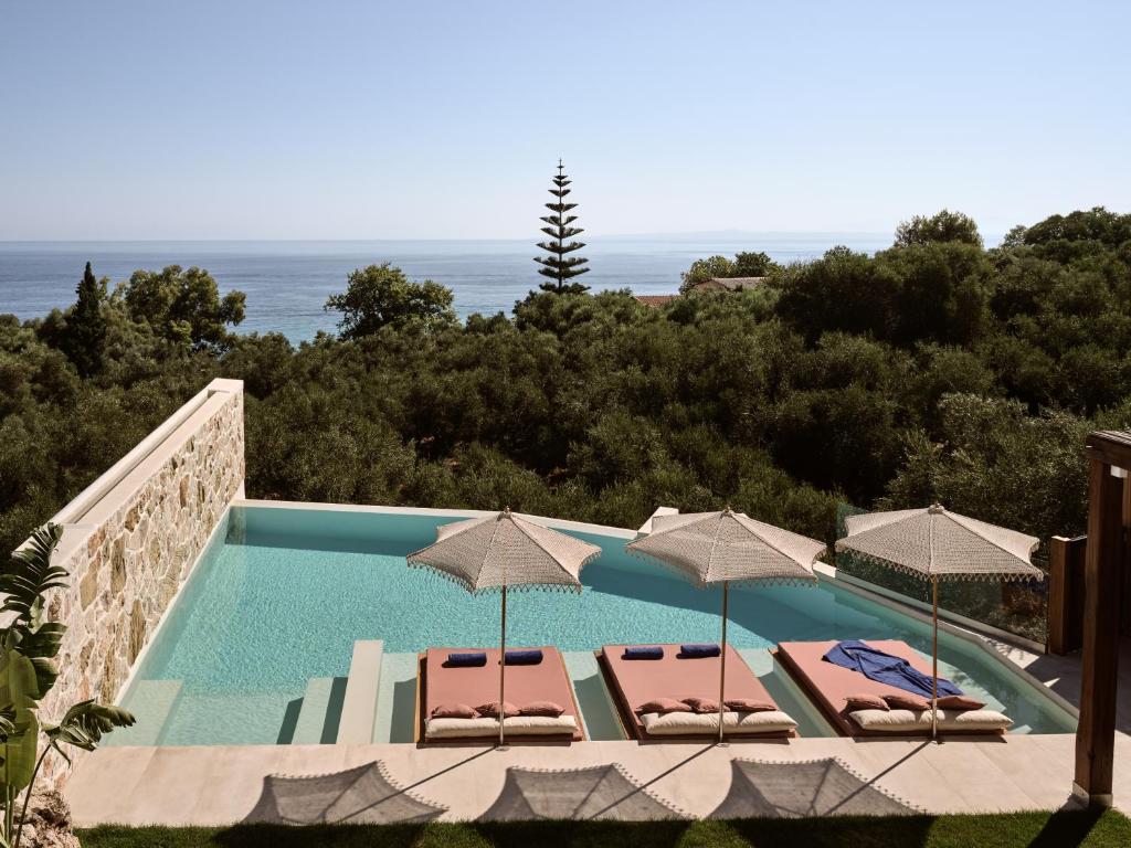 a swimming pool with two chairs and umbrellas at Ismet Villa, a SeaView Glorious Hideaway, By ThinkVilla in Akrotiri