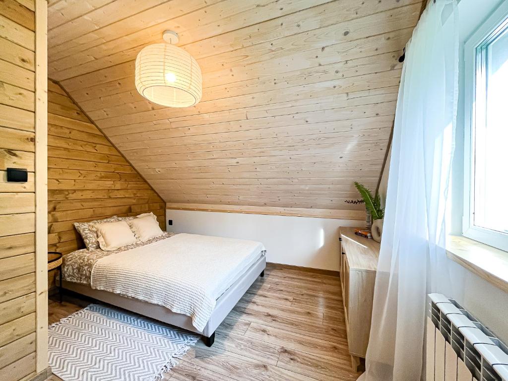 ZaBieszczaduj - apartamenty do wynajęcia في لوتوويسكا: غرفة نوم بسرير في منزل خشبي