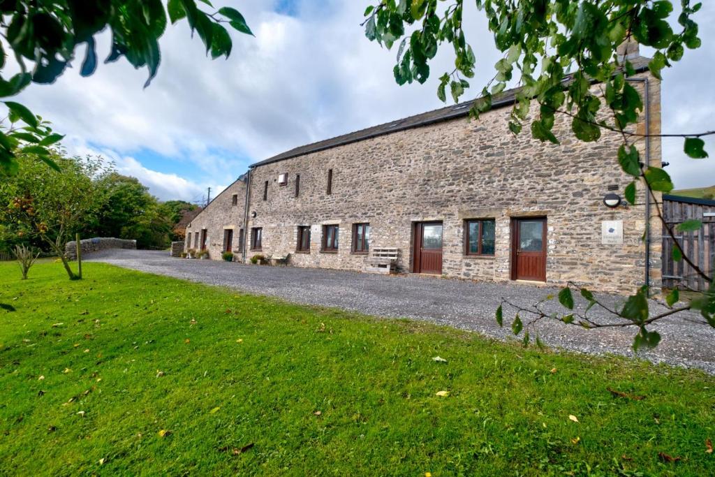 an external view of a stone building with a green field at Barn in Sedbergh