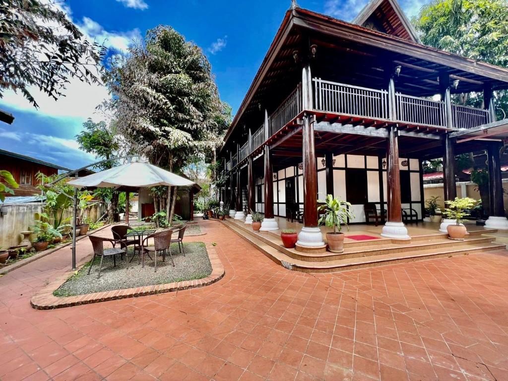 a building with a patio with a table and an umbrella at Villa Vieng Sa Vanh Hotel in Luang Prabang