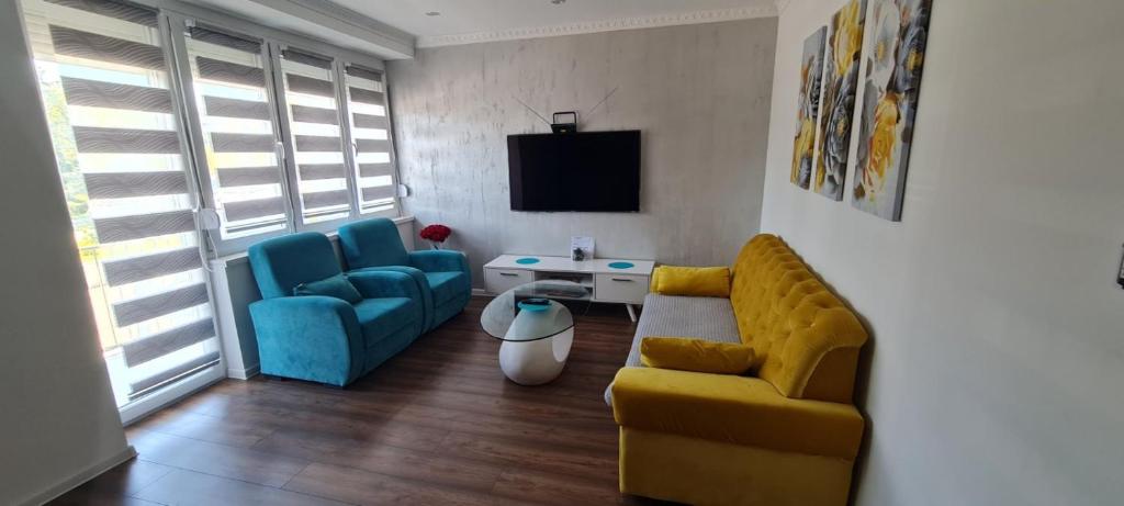 uma sala de estar com um sofá amarelo e cadeiras azuis em LARA S em Banja Luka