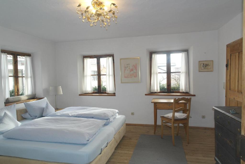 um quarto com uma cama, uma mesa e janelas em Bel Etage - Historisches Refugium in der Altstadt von Ebersberg em Ebersberg