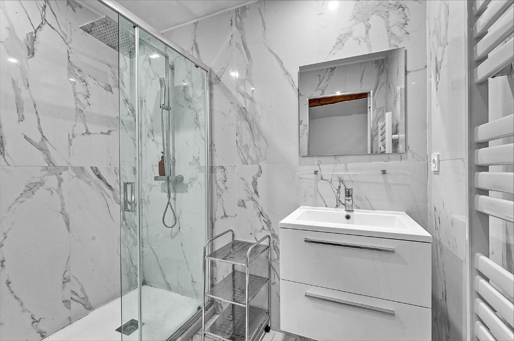 a white bathroom with a shower and a sink at Les Relais du Capitole - Appartements d'hôtes in Toulouse