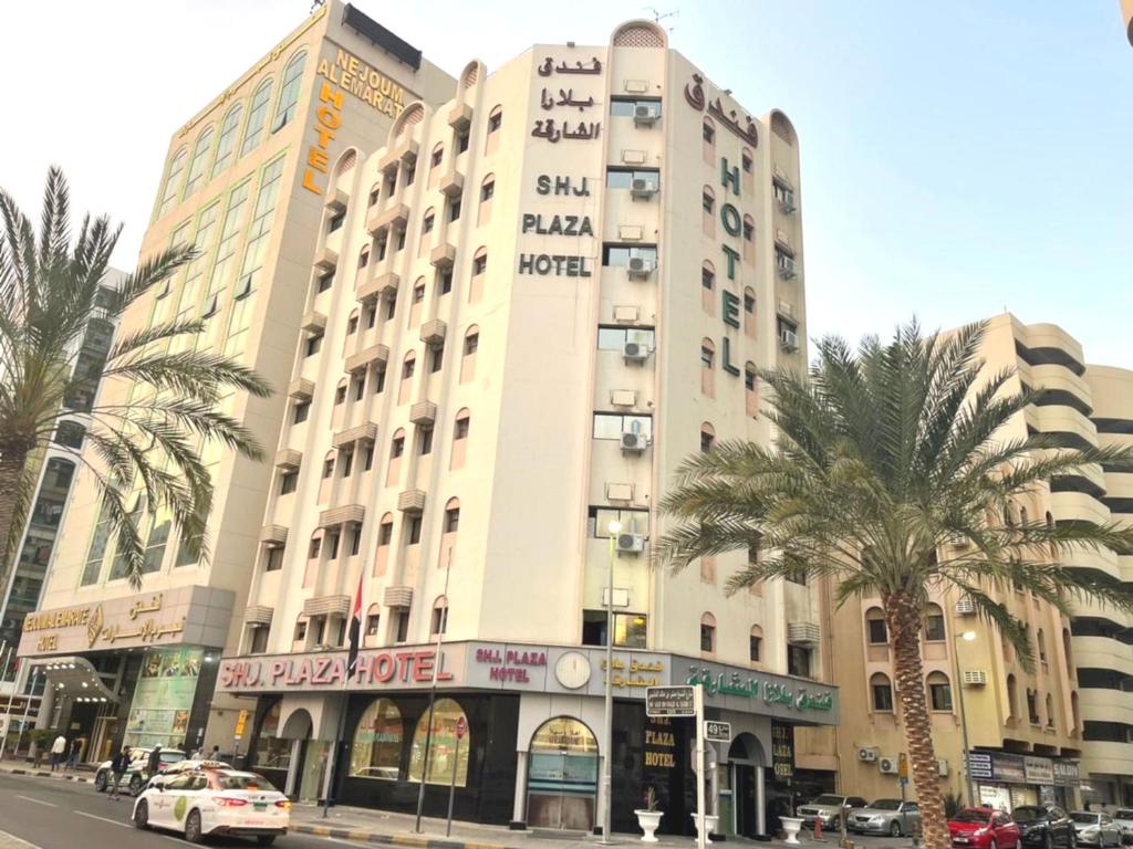 um grande edifício numa rua da cidade com palmeiras em Sharjah Plaza Hotel em Sharjah
