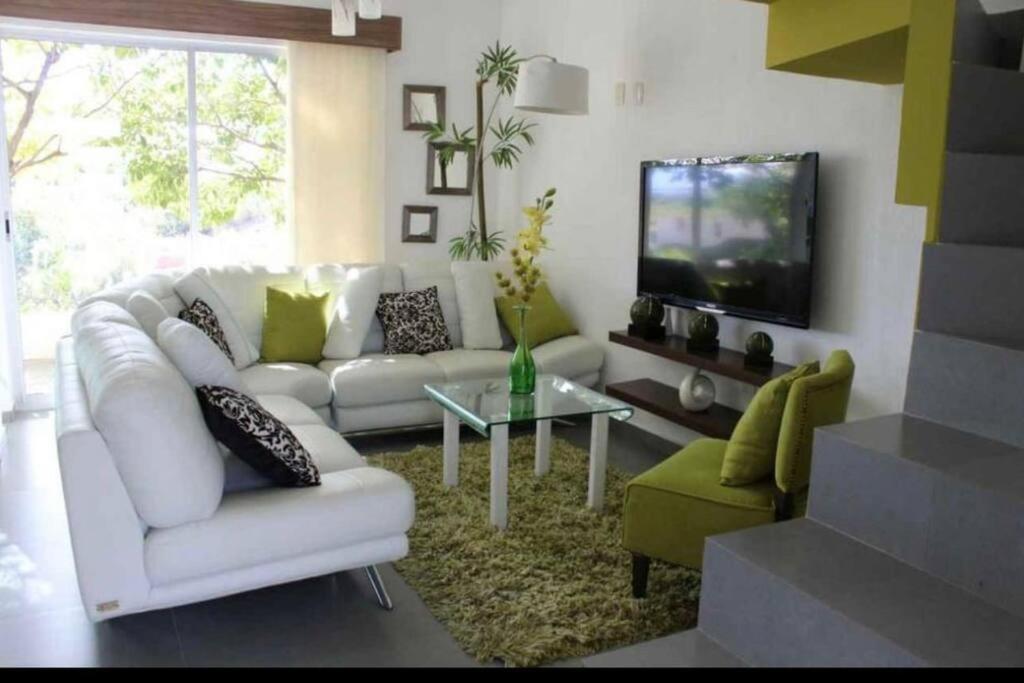 casa green con club de alberca في تيبيك: غرفة معيشة مع أريكة بيضاء وتلفزيون