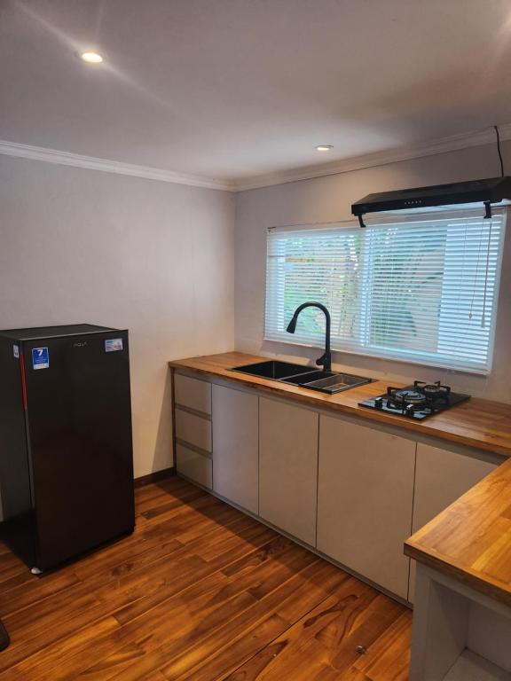 een keuken met een wastafel en een zwarte koelkast bij Modern LOFT studio apartment in Sanur