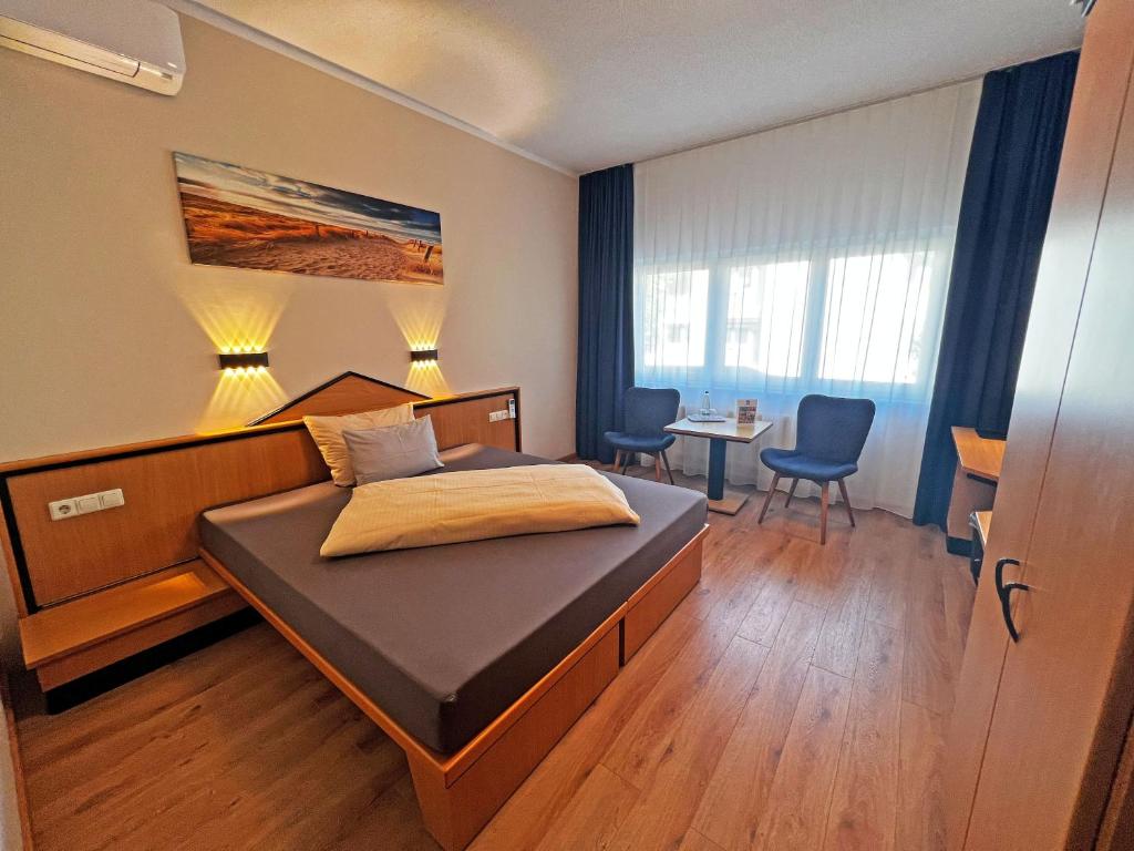 Schlafzimmer mit einem Bett, einem Tisch und Stühlen in der Unterkunft HIL - Hotel im Lus Schopfheim in Schopfheim